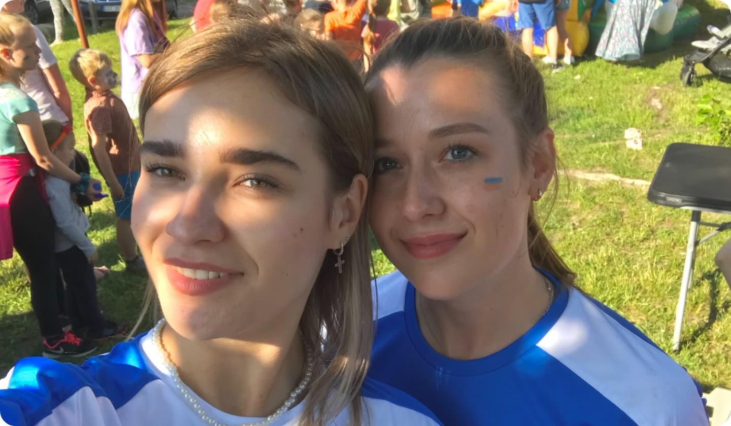 two young volunteer girls in white T-shirts with the flag of Ukraine painted on their cheeks